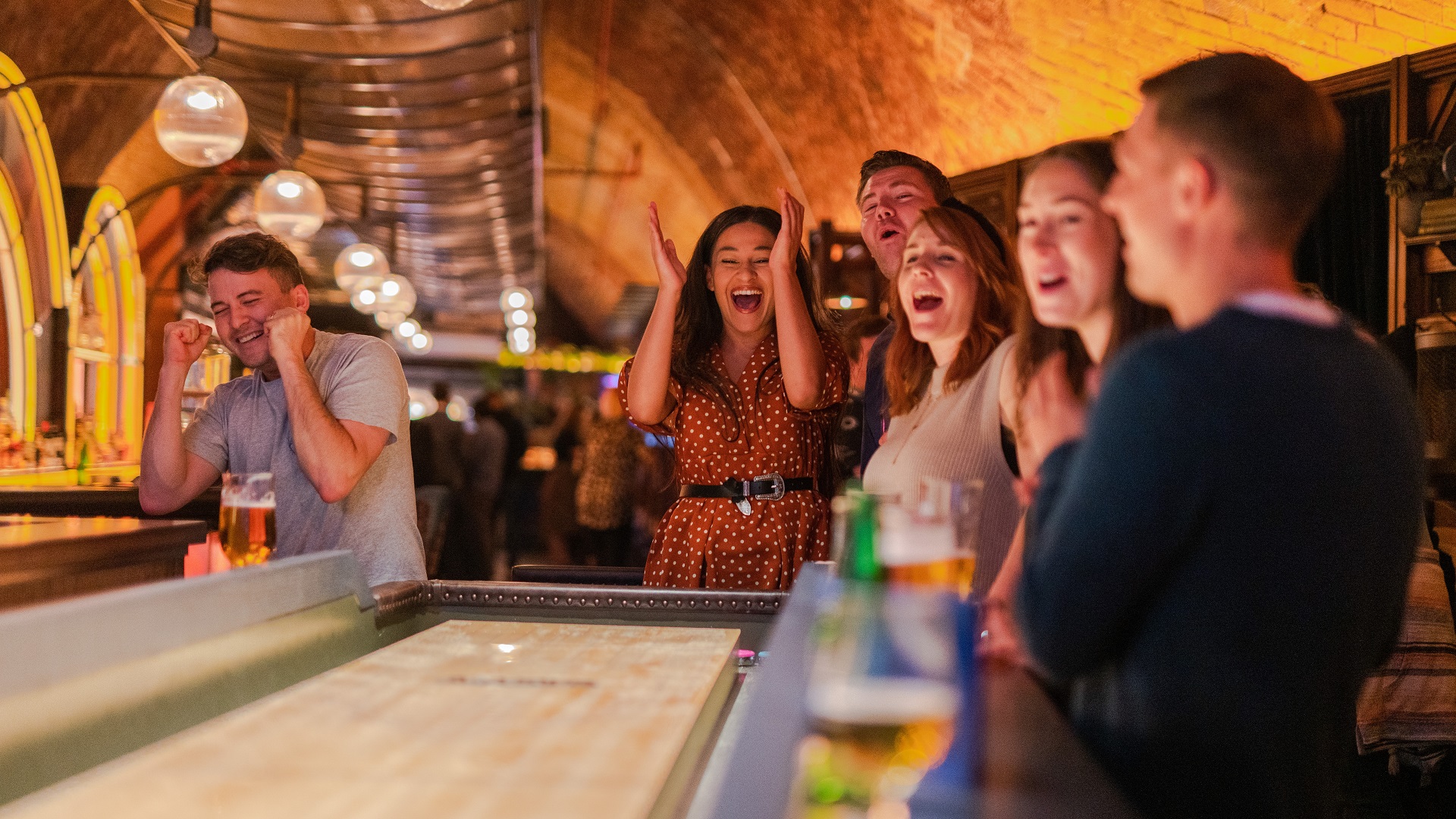 A group of people celebrating while playing Electric Shuffleboard at Electric Shuffle